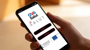 Hand hält Smartphone mit geöffnetem Startbildschirm der GVA Salut App, auf dem die Sprachoptionen „Valencià“ und „Castellano“ angezeigt werden.