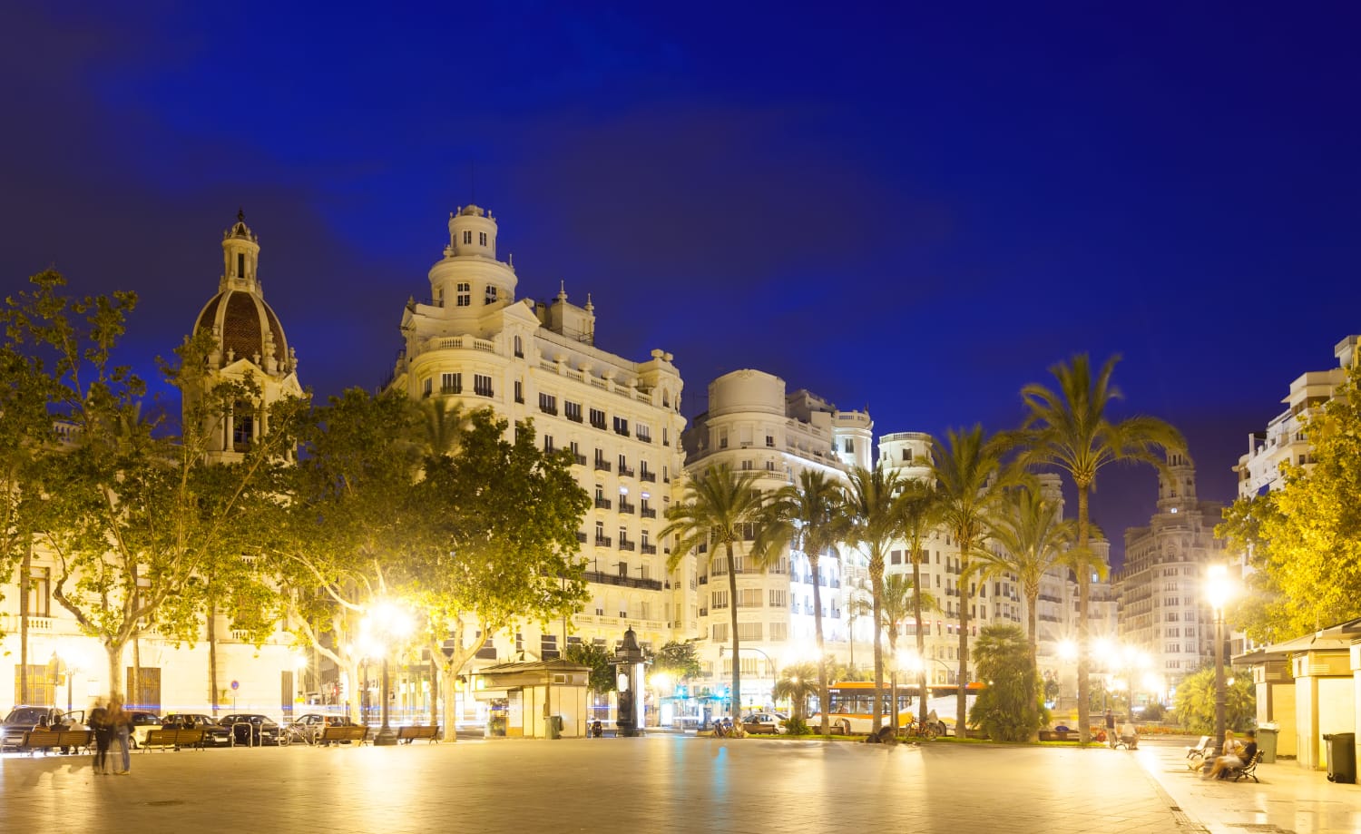Historische Gebäude und Palmen an einem beleuchteten Platz bei Nacht in Valencia
