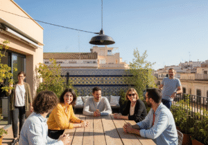 Co-Living in Valencia: Menschen auf einer sonnigen Dachterrasse erleben modernes Gemeinschaftswohnen mit Stadtblick und mediterranem Flair. KI-generiert mit Google Imagen 4.
